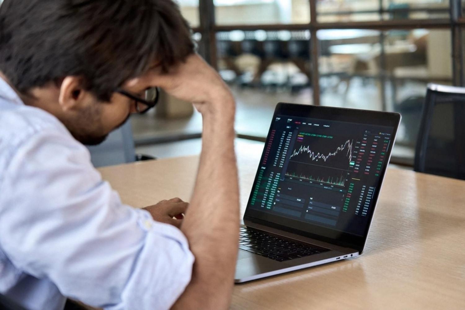 Business owner reviewing financial charts on a laptop while considering compliance risks